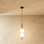 Clérachic two-ball orb pendant light in a matte black finish, both globes glowing warm on one slim rod.