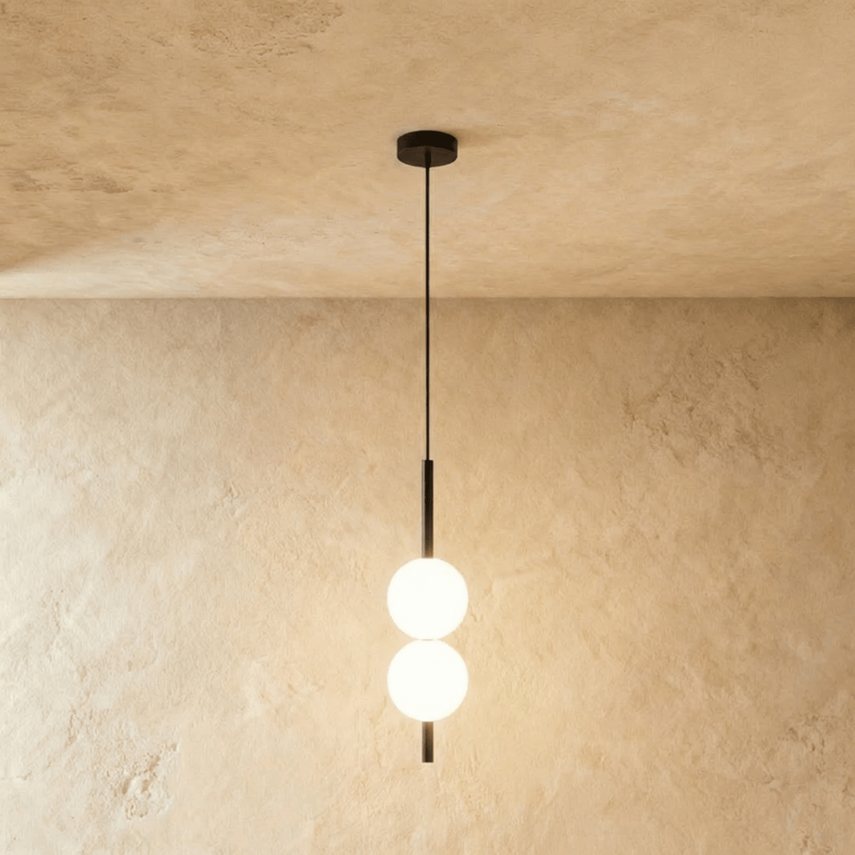 Clérachic two-ball orb pendant light in a matte black finish, both globes glowing warm on one slim rod.