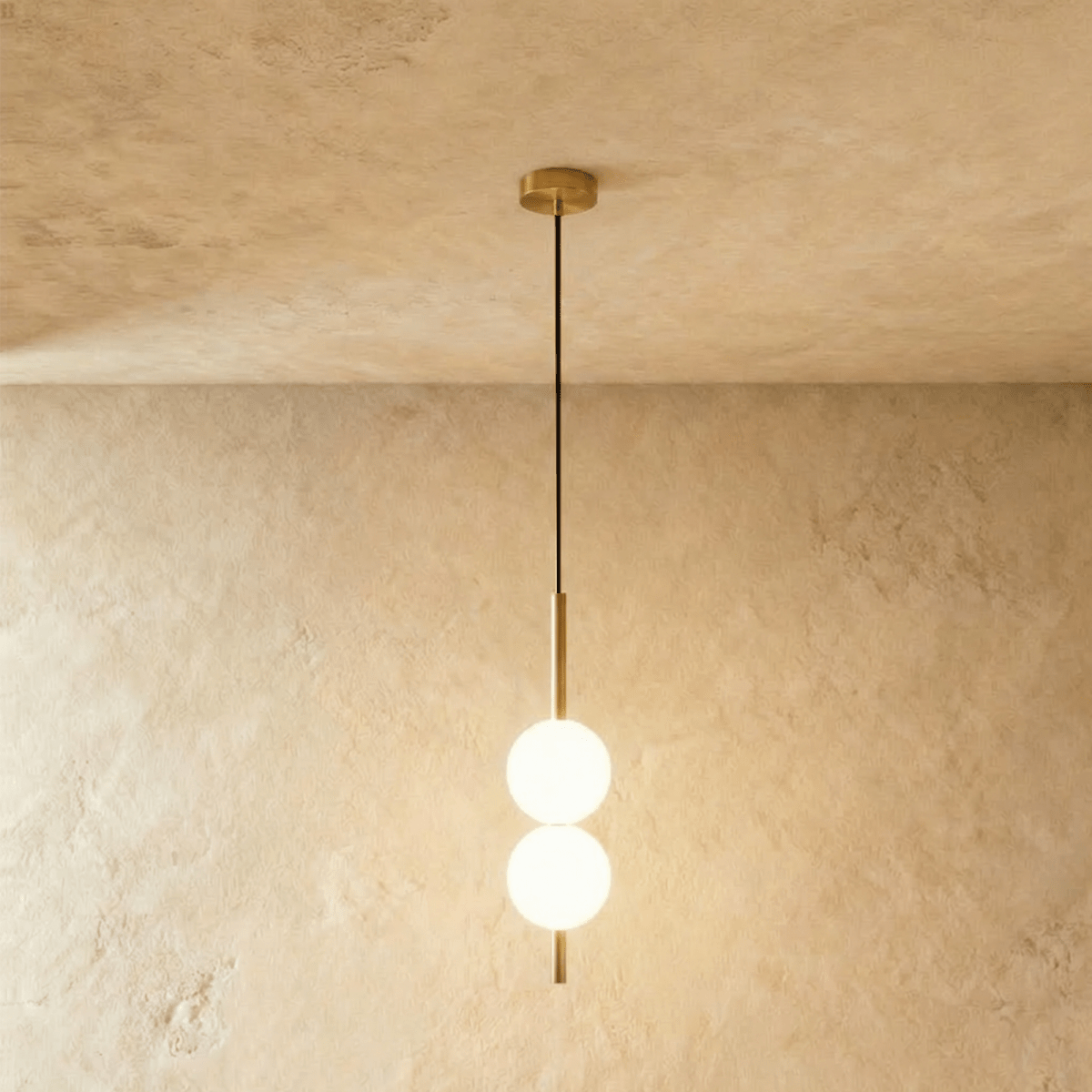 Clérachic two-ball orb pendant light in a brushed brass finish, both globes glowing warm on one slim rod.