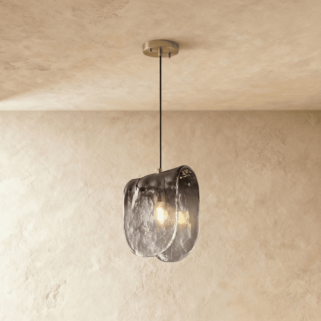Clérachic single pendant with a smoke-grey gradient glass shade, lit warm from a filament bulb against limewash.