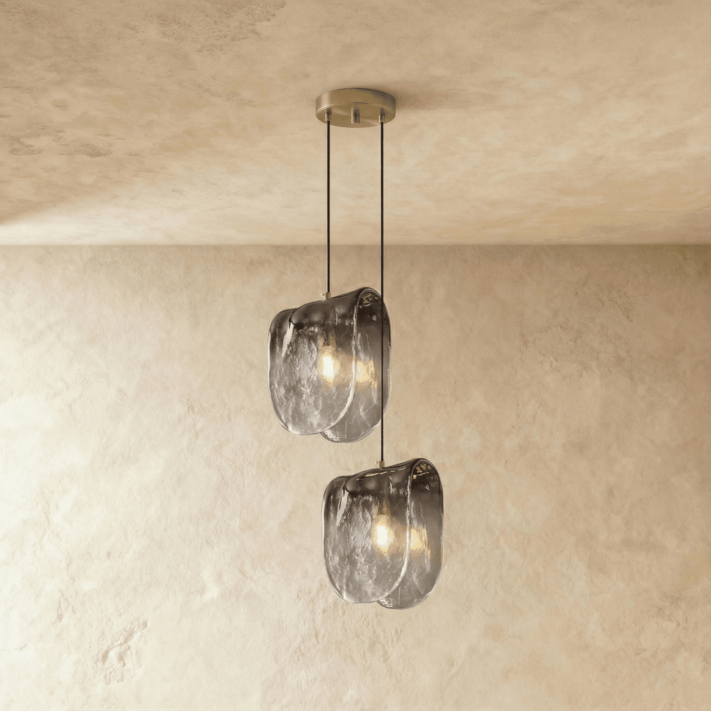 Clérachic two-head glass pendant glowing warm, its rippled smoke-grey shades hanging at two heights on plaster.