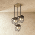 Clérachic three-head round pendant lit warm, with rippled smoke-grey glass shades on a brushed round ceiling plate.