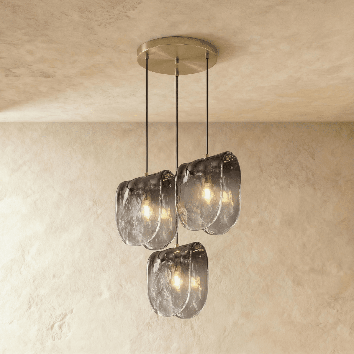 Clérachic three-head round pendant lit warm, with rippled smoke-grey glass shades on a brushed round ceiling plate.
