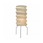 Clérachic pleated rice-paper floor lamp lit on a plain white background, the small ball feet of its three legs resting on the floor.