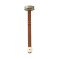 Studio front view of the Clérachic Orinos pendant: a riveted cognac strap carrying one alabaster disc from a brass canopy.