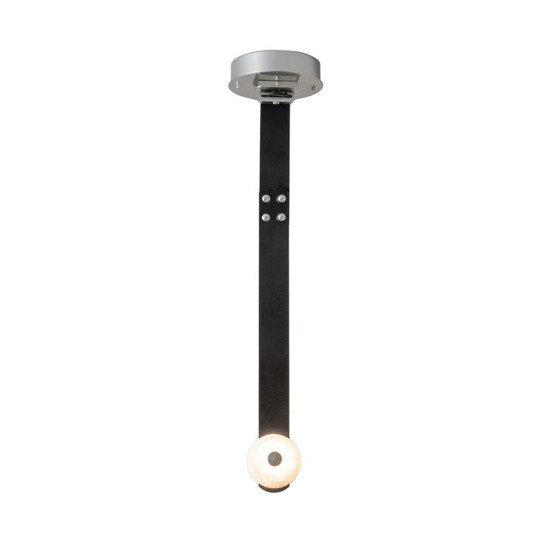 Front view of the black-leather Clérachic Orinos, the alabaster disc glowing at the end of the riveted strap.