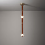 The two-head Clérachic Orinos straight drop, alabaster discs spaced along a riveted cognac strap against a plain wall.