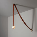 Clérachic Orinos ceiling-to-wall layout: one alabaster head on a cognac strap angled back to a brass wall bracket.