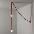 Two-head Clérachic Orinos on the diagonal, both alabaster discs lit where the strap turns down from the wall bracket.