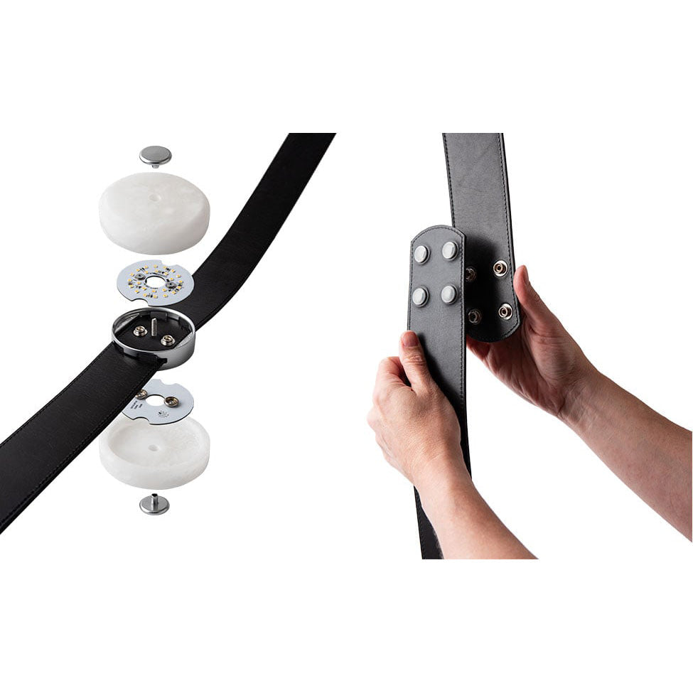 Exploded view of a Clérachic Orinos head — alabaster caps, LED board and housing — beside hands pressing the strap studs.