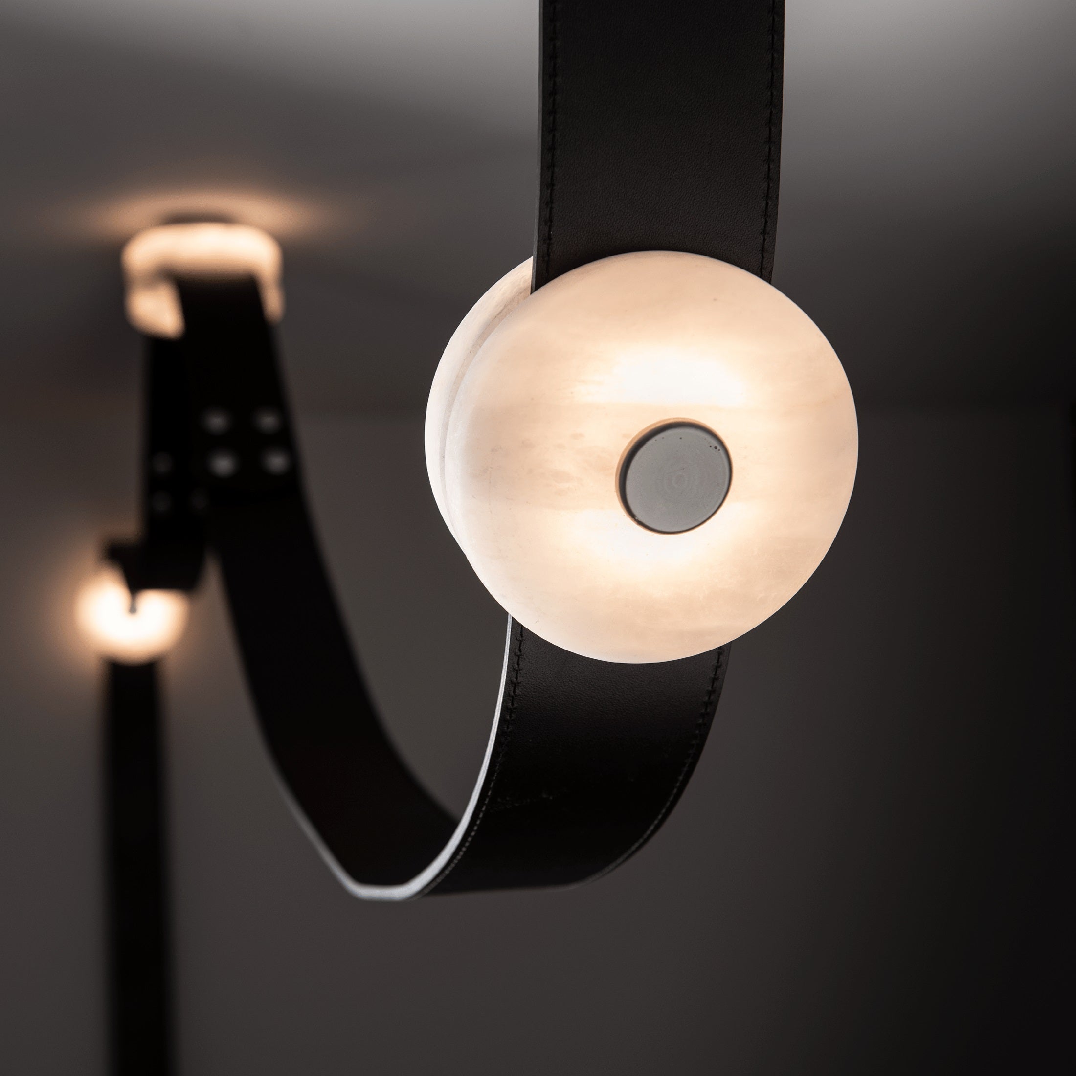 Two Clérachic Orinos heads on black leather, the nearest alabaster disc sharp and the second glowing behind it.