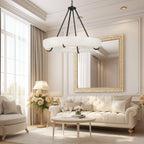 Clérachic Orion chandelier lighting a cream living room with a gilt mirror and tufted sofas.
