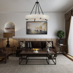 Clérachic Orion alabaster chandelier in a dark-toned living room beneath a large maritime painting.