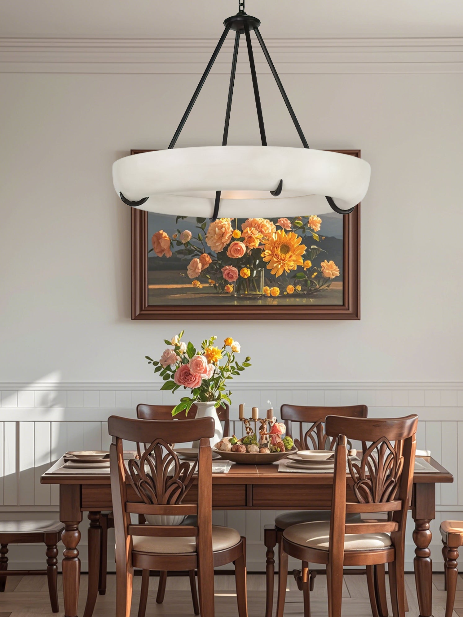 Clérachic Orion chandelier above a wooden dining table set with roses and lit candles.