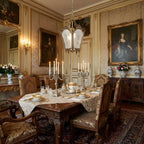 Frosted-glass brass lantern hung in a panelled dining room with candelabras and a large gilt-framed portrait, from Clérachic.