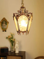 Clérachic brass lantern pendant lit above a console with a vase of flowers and a small white statue.