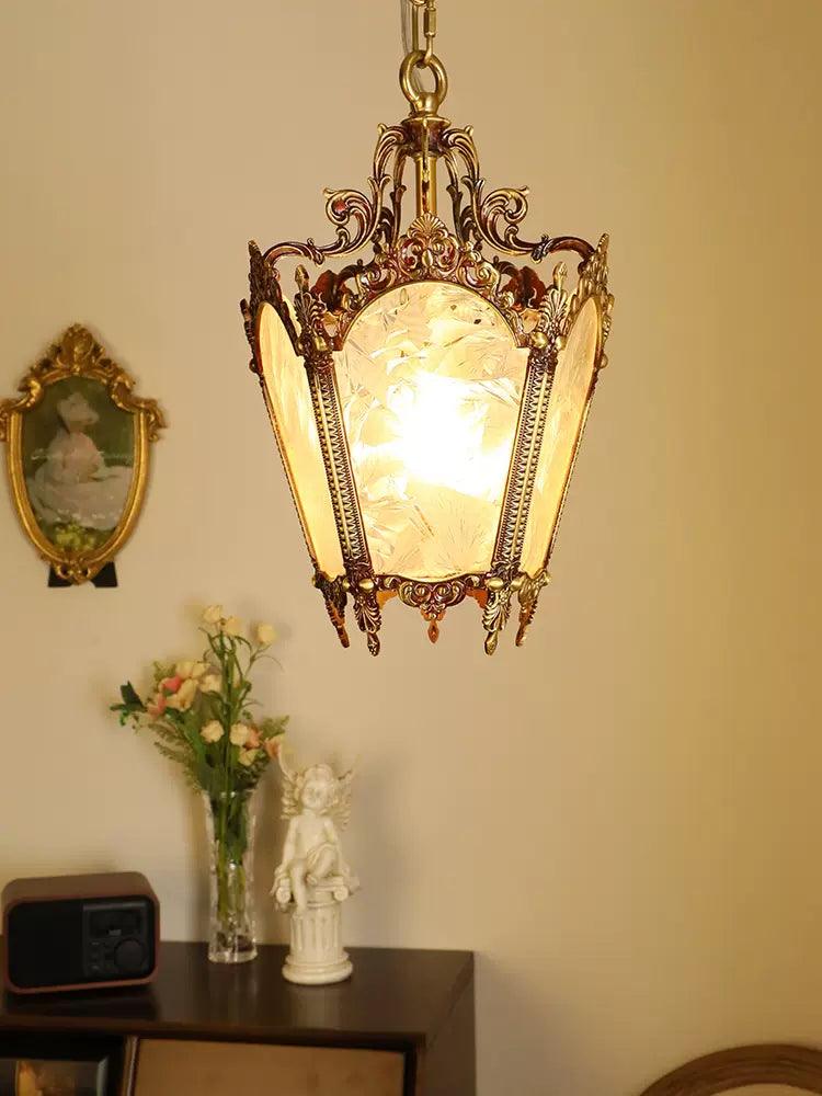Clérachic brass lantern pendant lit above a console with a vase of flowers and a small white statue.