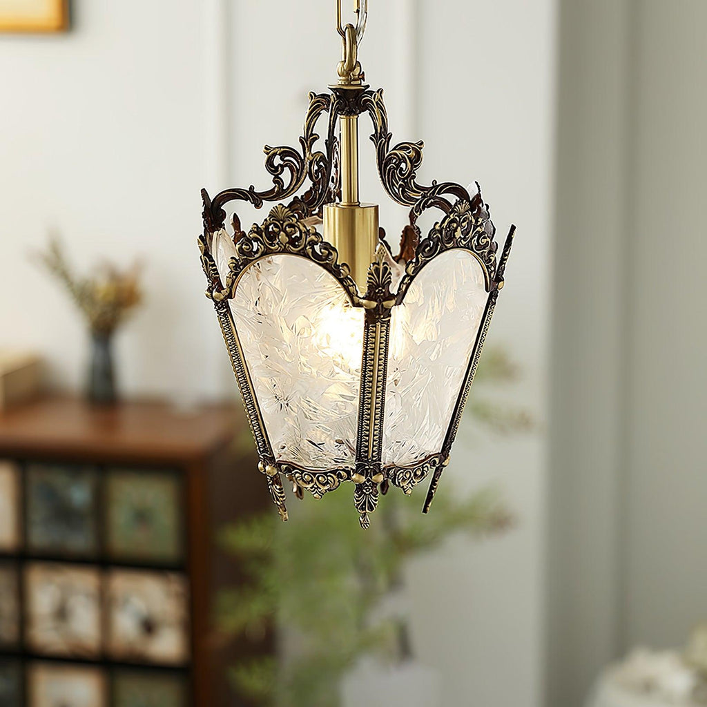 Clérachic brass lantern pendant with an aged dark-brass frame, hung before a wooden cabinet and blurred greenery.