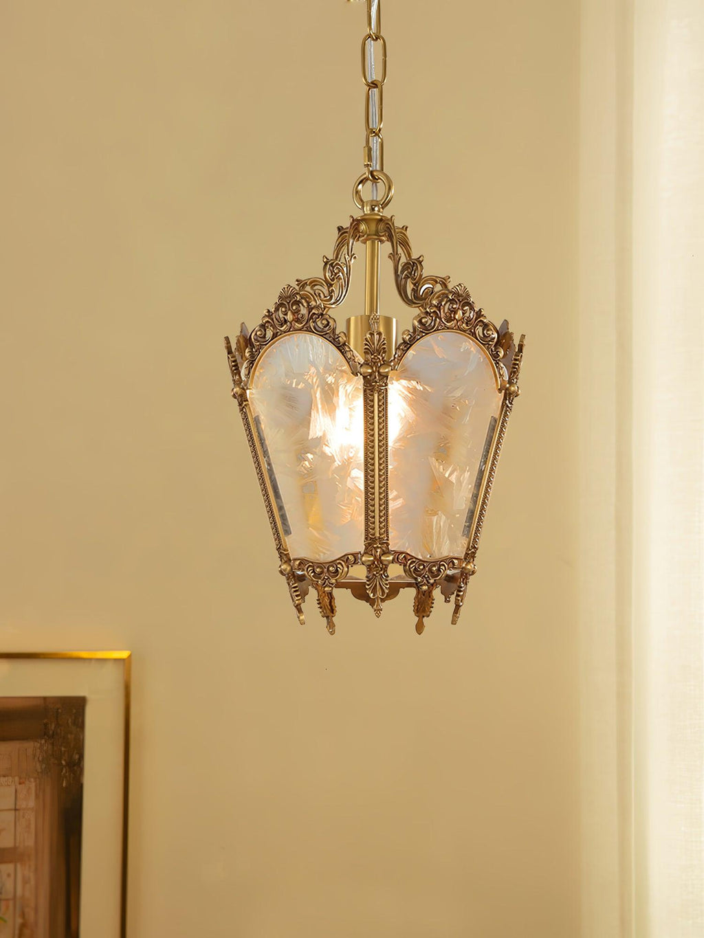 Brass lantern pendant with frosted glass panes hung against a warm cream wall, from Clérachic.