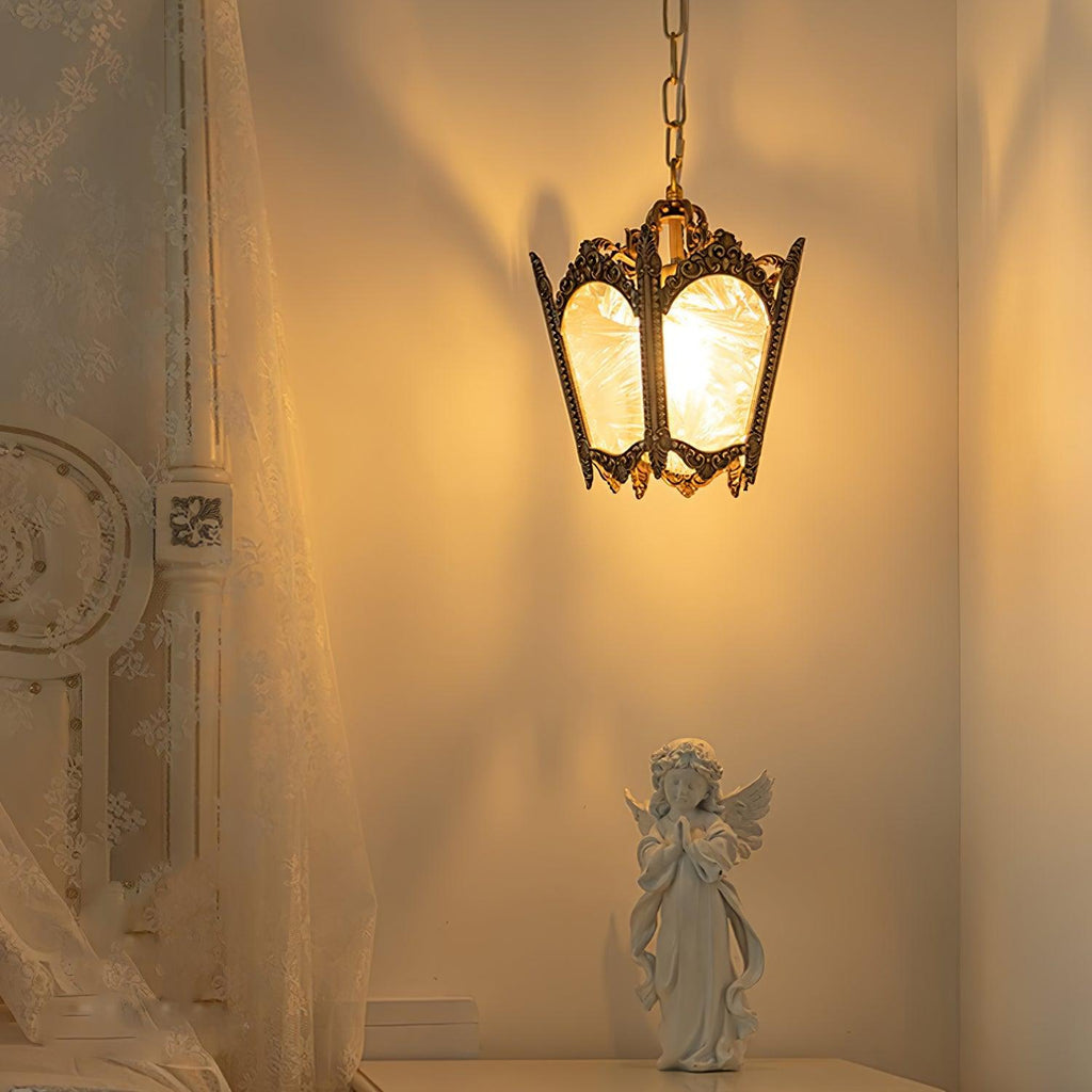 Lit brass lantern pendant casting a warm glow over a curtain and a small angel figure on a shelf, from Clérachic.