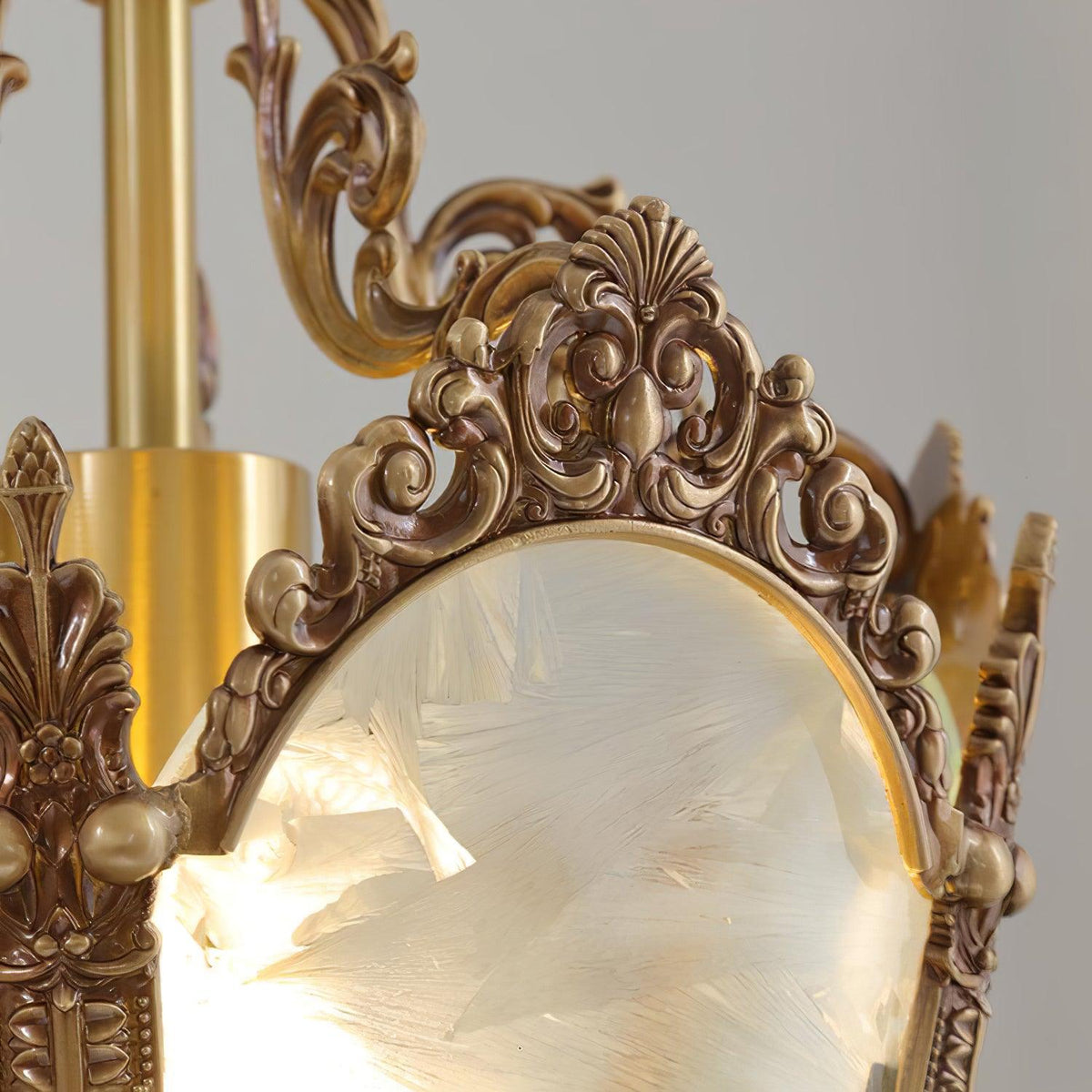 Close view of the scrolled brass crown and the brass stem above one frosted pane on this Clérachic lantern.