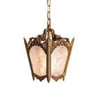 Front view of a brass lantern with intricate cast scrollwork and frosted panes, on a plain white backdrop, from Clérachic.