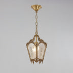 Brass lantern pendant under a domed ceiling canopy, with a short chain and frosted panes, on a pale grey backdrop, from Clérachic.