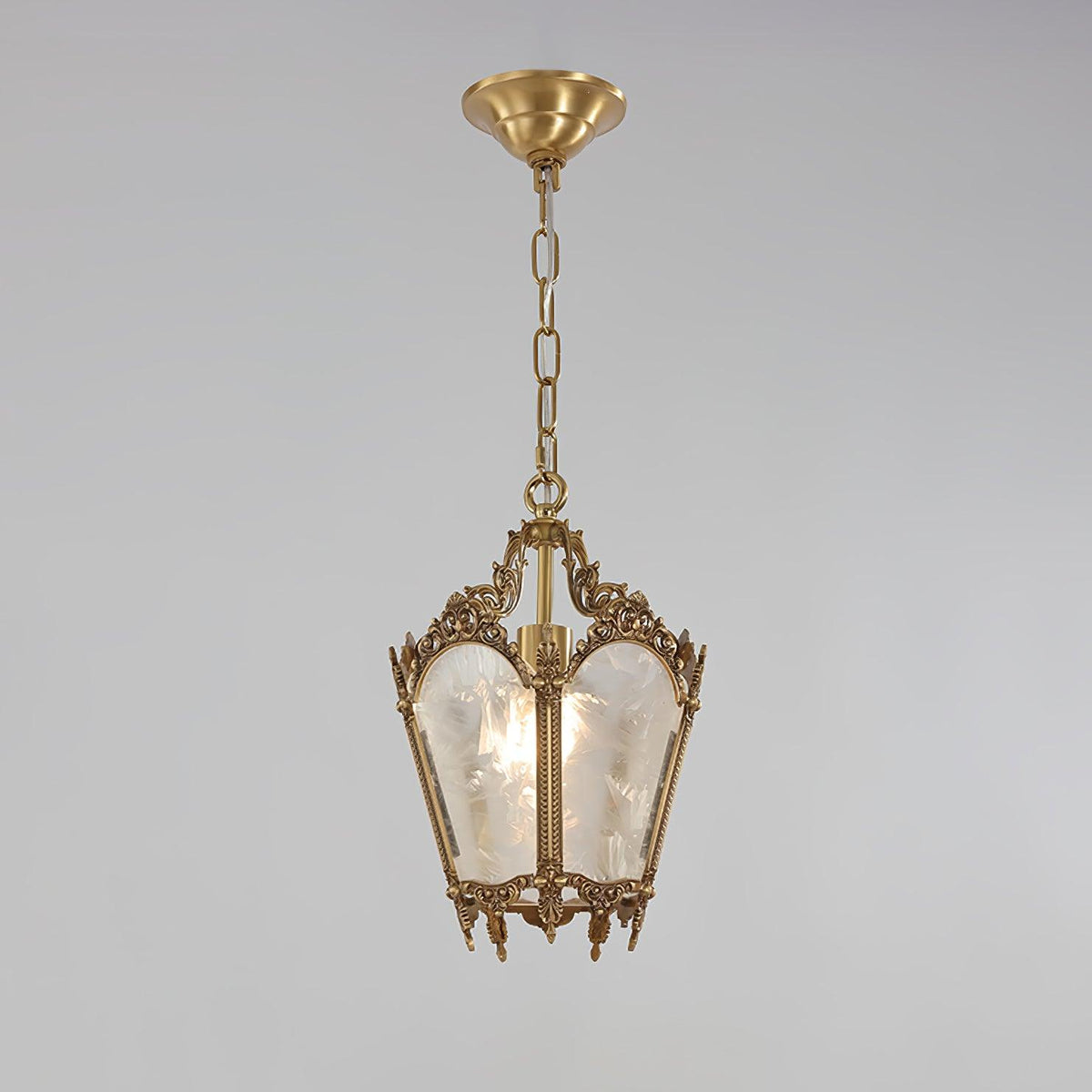 Brass lantern pendant under a domed ceiling canopy, with a short chain and frosted panes, on a pale grey backdrop, from Clérachic.