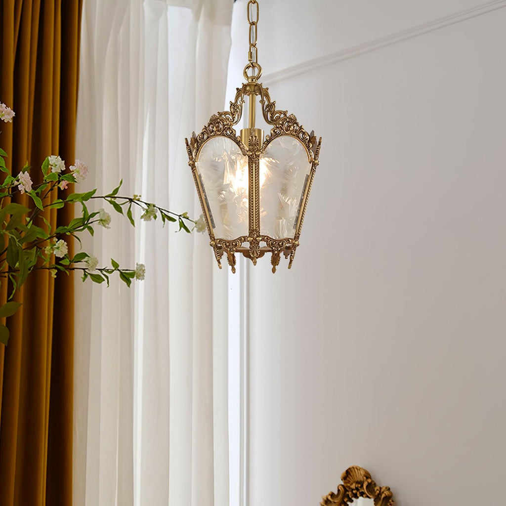 Clérachic brass lantern pendant hung by tall white curtains with a mustard drape and a flowering branch.
