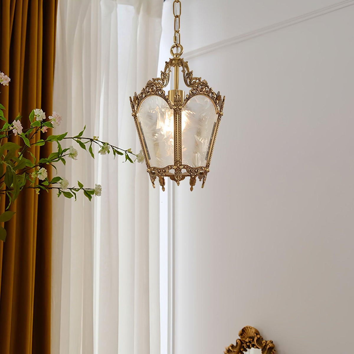 Clérachic brass lantern pendant hung by tall white curtains with a mustard drape and a flowering branch.