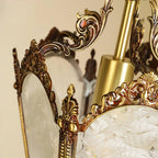 Close view of the cast brass scrolls and acanthus-like finial where two frosted panes meet, on this Clérachic lantern.