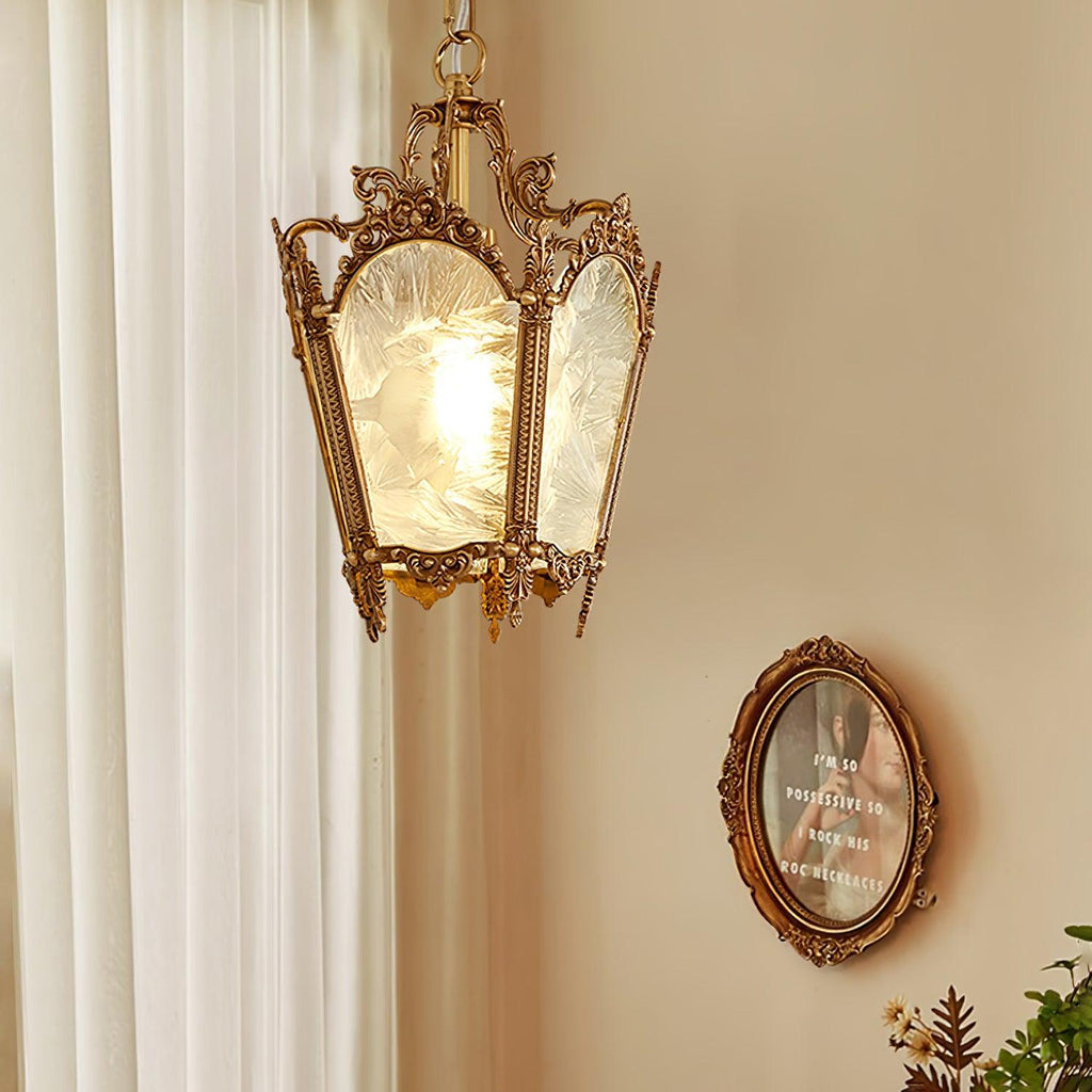 Brass lantern pendant lit beside a sheer curtain, with a small oval frame on the wall behind, from Clérachic.