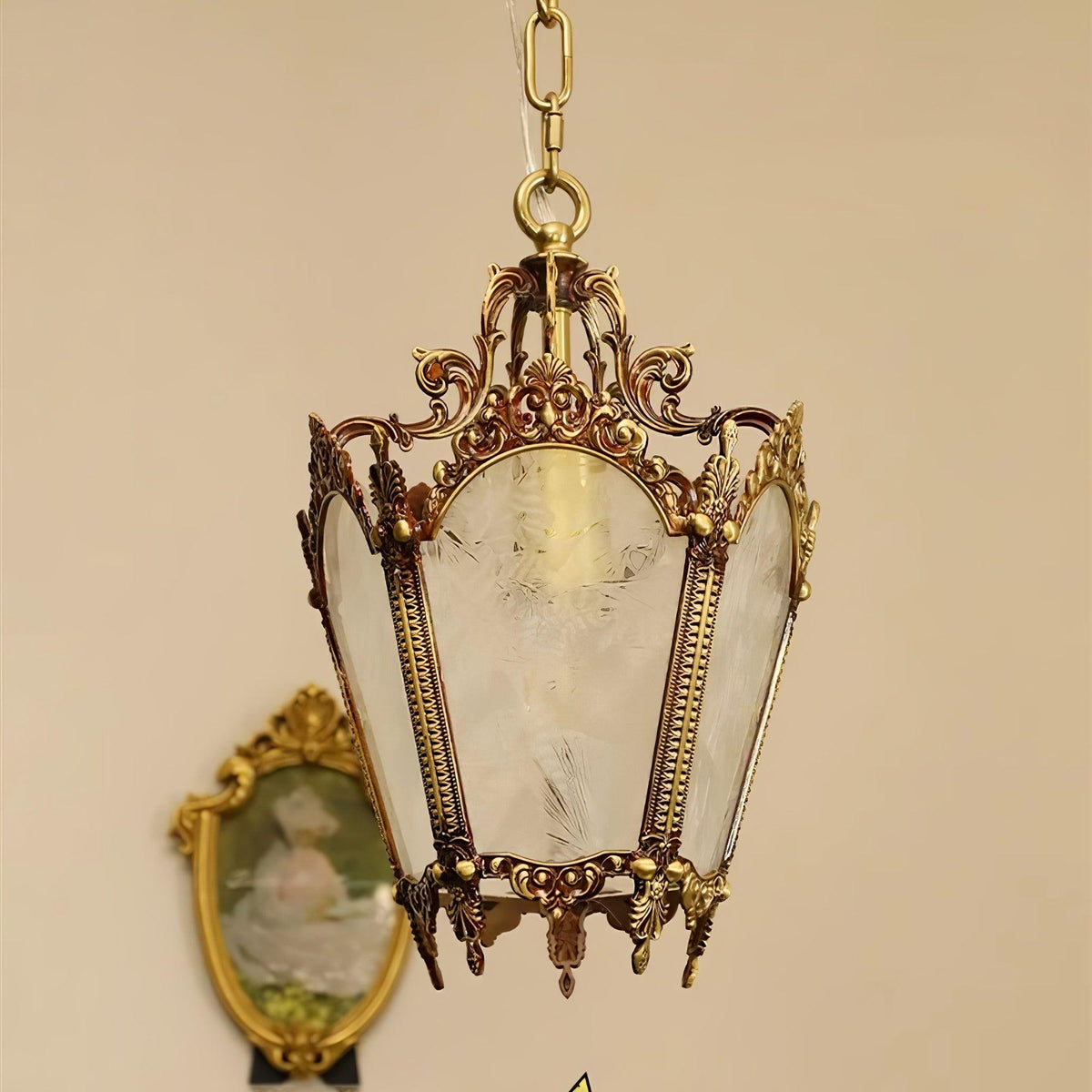 Clérachic brass lantern pendant against a peach wall, in front of a gilt oval portrait, with frosted panes showing.