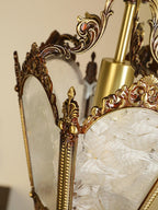 Close view of the frosted glass panes, brass post and scrolled crown at the top of this Clérachic lantern.
