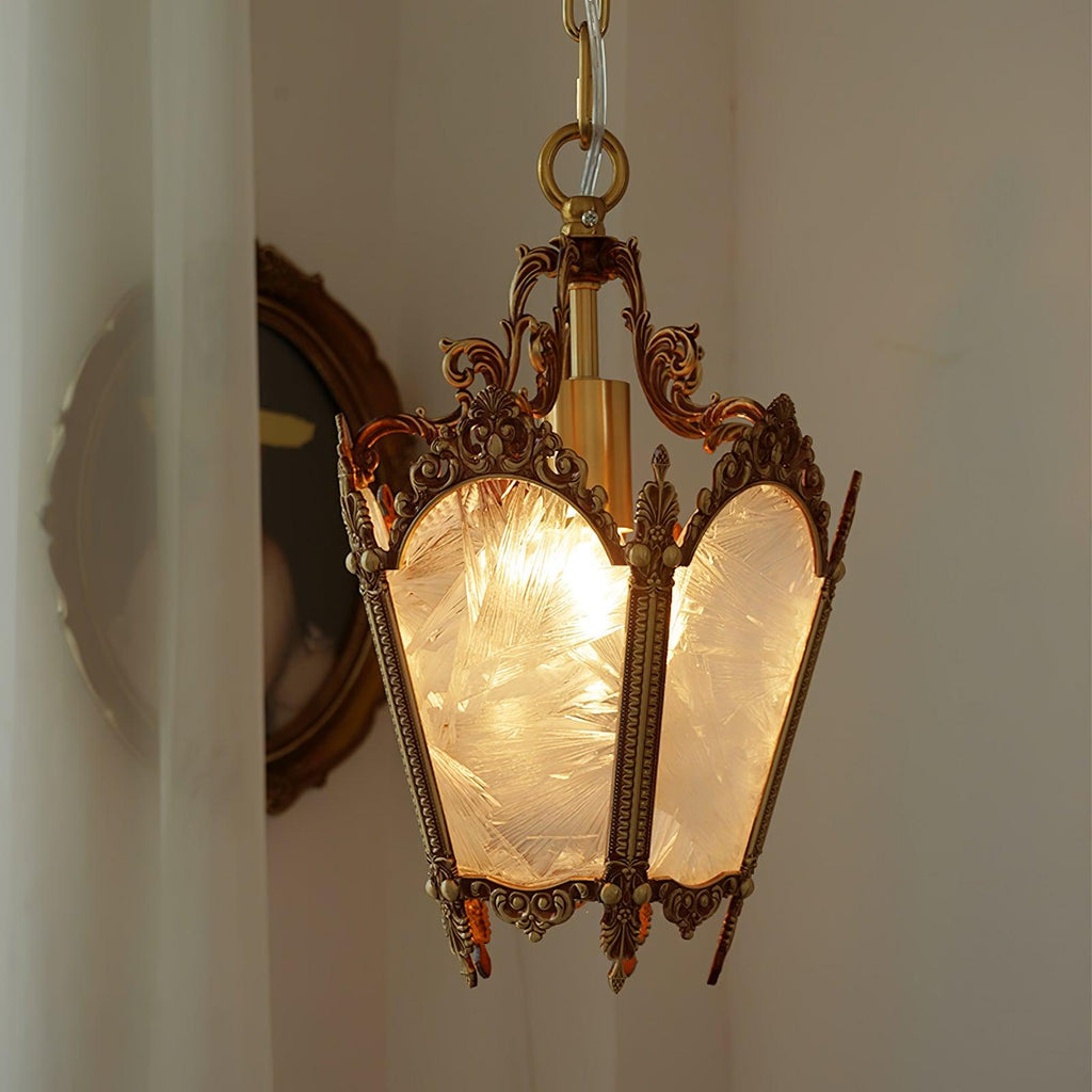 Warm light inside this Clérachic brass lantern pendant, hung against a curtain beside an oval portrait.