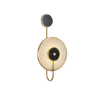 Clérachic Orphaa in a plain studio view, the brass loop tail curving neatly beneath the pale alabaster disc.