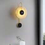 The Clérachic Orphaa angled on a grey wall, its warm wash spilling down toward a slim vase below the window.
