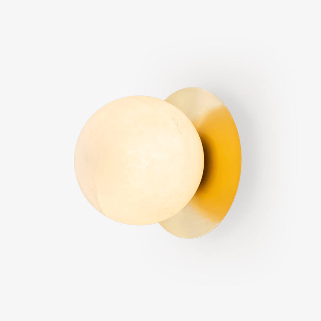 Clérachic Orrila sconce on white, showing the full brass plate and veined alabaster sphere.