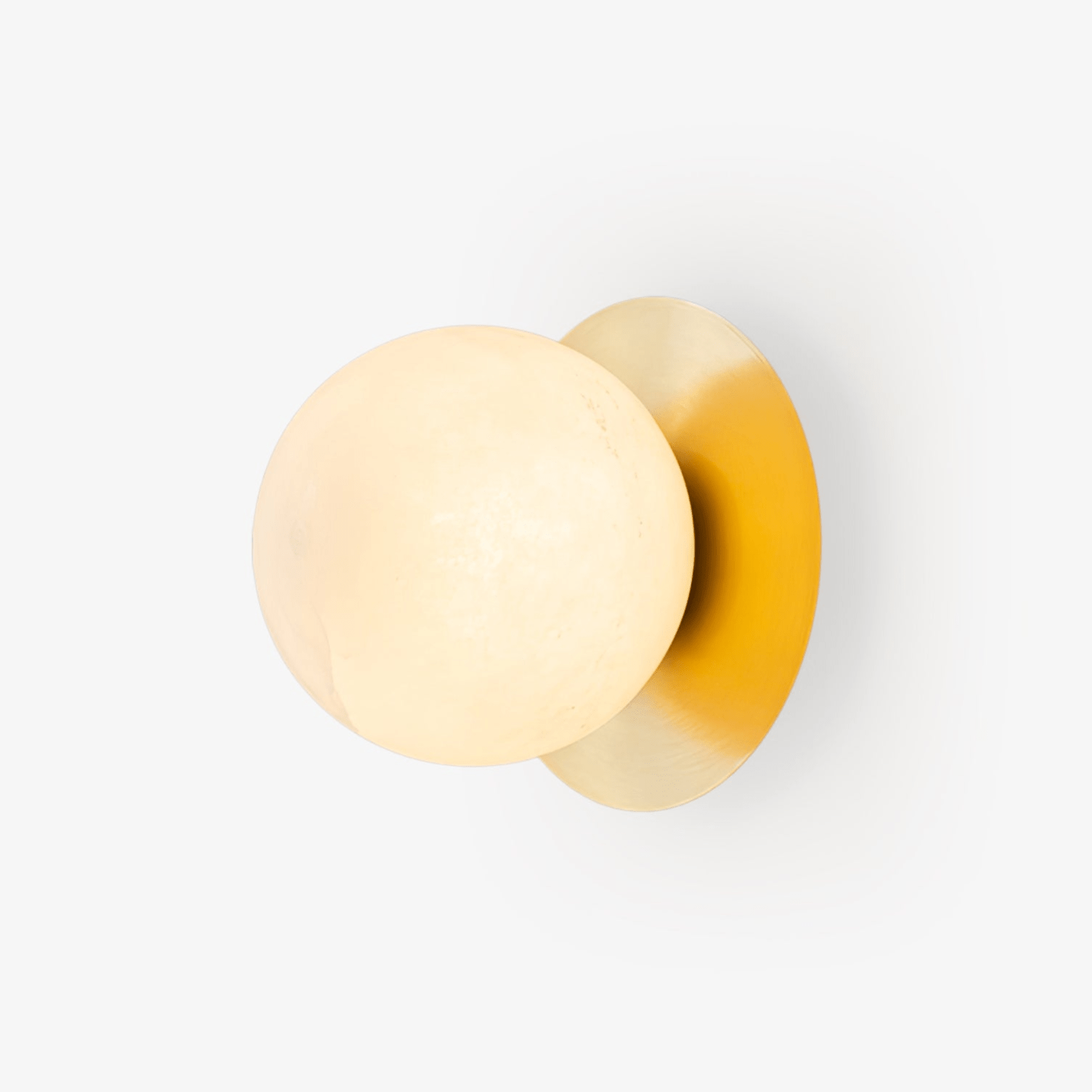 Clérachic Orrila sconce on white, showing the full brass plate and veined alabaster sphere.