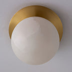 Close view of the Clérachic Orrila ceiling mount, brass plate curving over the stone globe.