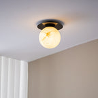 Clérachic Orrila in black finish on a ceiling, warm alabaster globe below the dark disc.