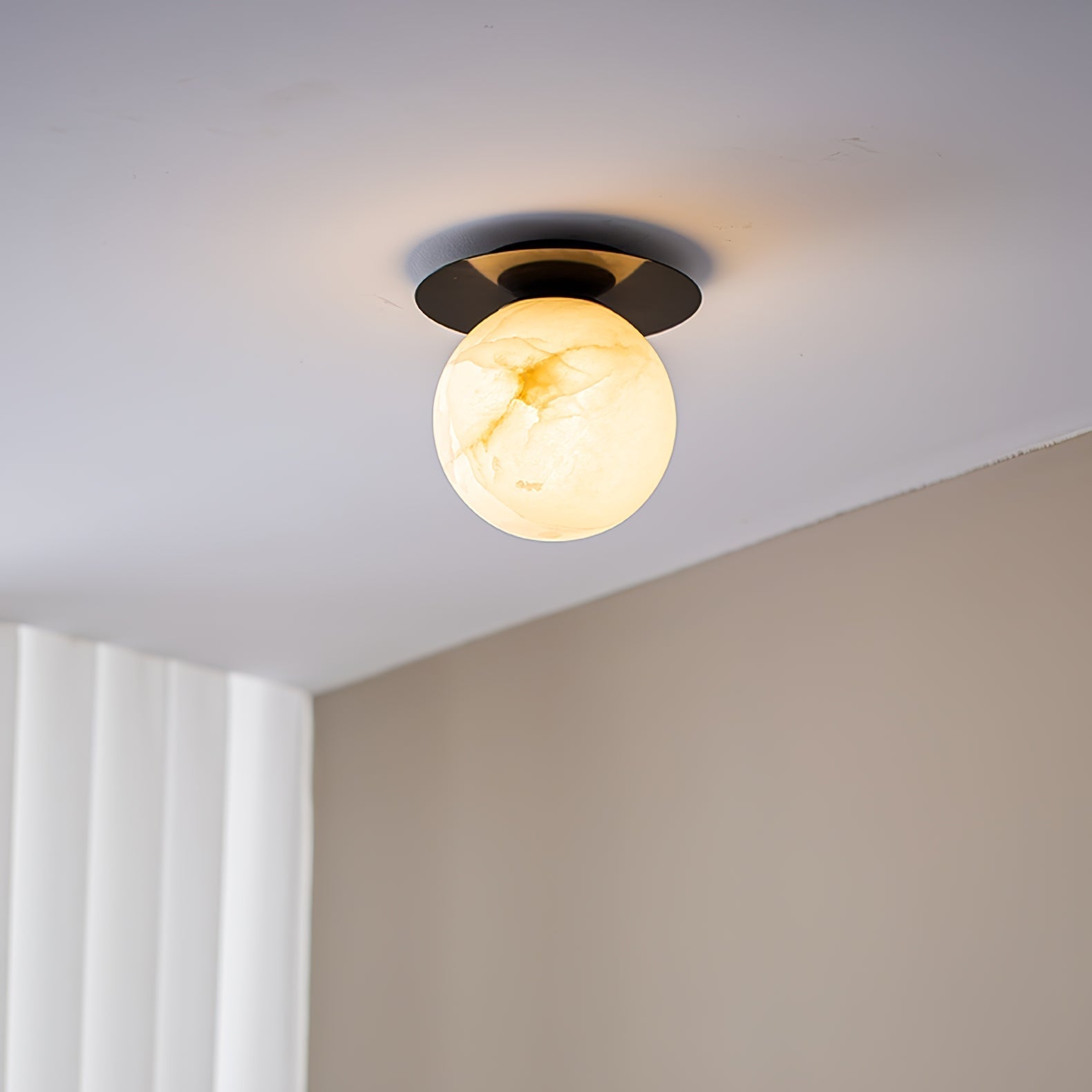 Clérachic Orrila in black finish on a ceiling, warm alabaster globe below the dark disc.