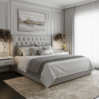 Two Clérachic feather table lamps with taupe plumes on bedside tables, either side of a grey tufted bed in a pale panelled bedroom.