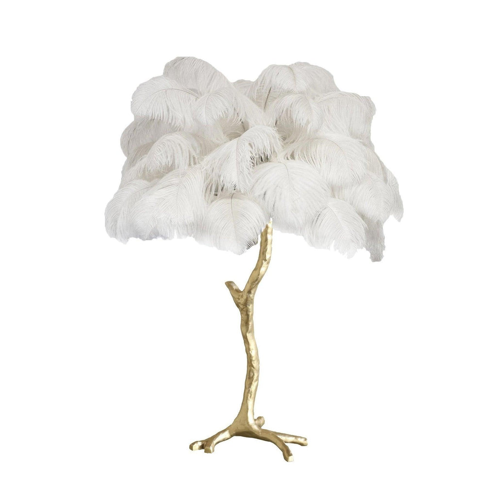 Clérachic table lamp with fluffy white ostrich feathers on a gold branch stem with splayed feet, on a plain white background.