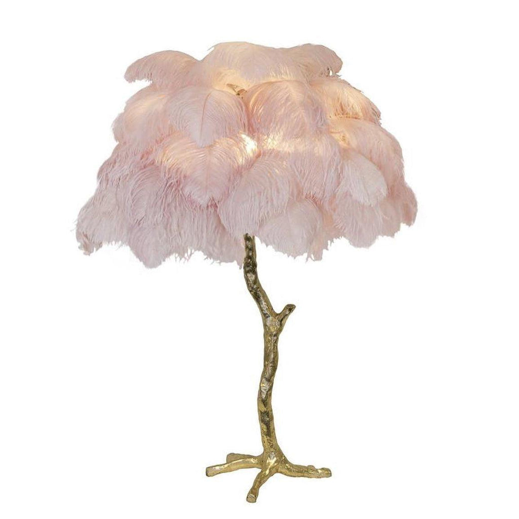 Clérachic table lamp with blush-pink feathers on a gold branch stem with splayed feet, on a plain white background.