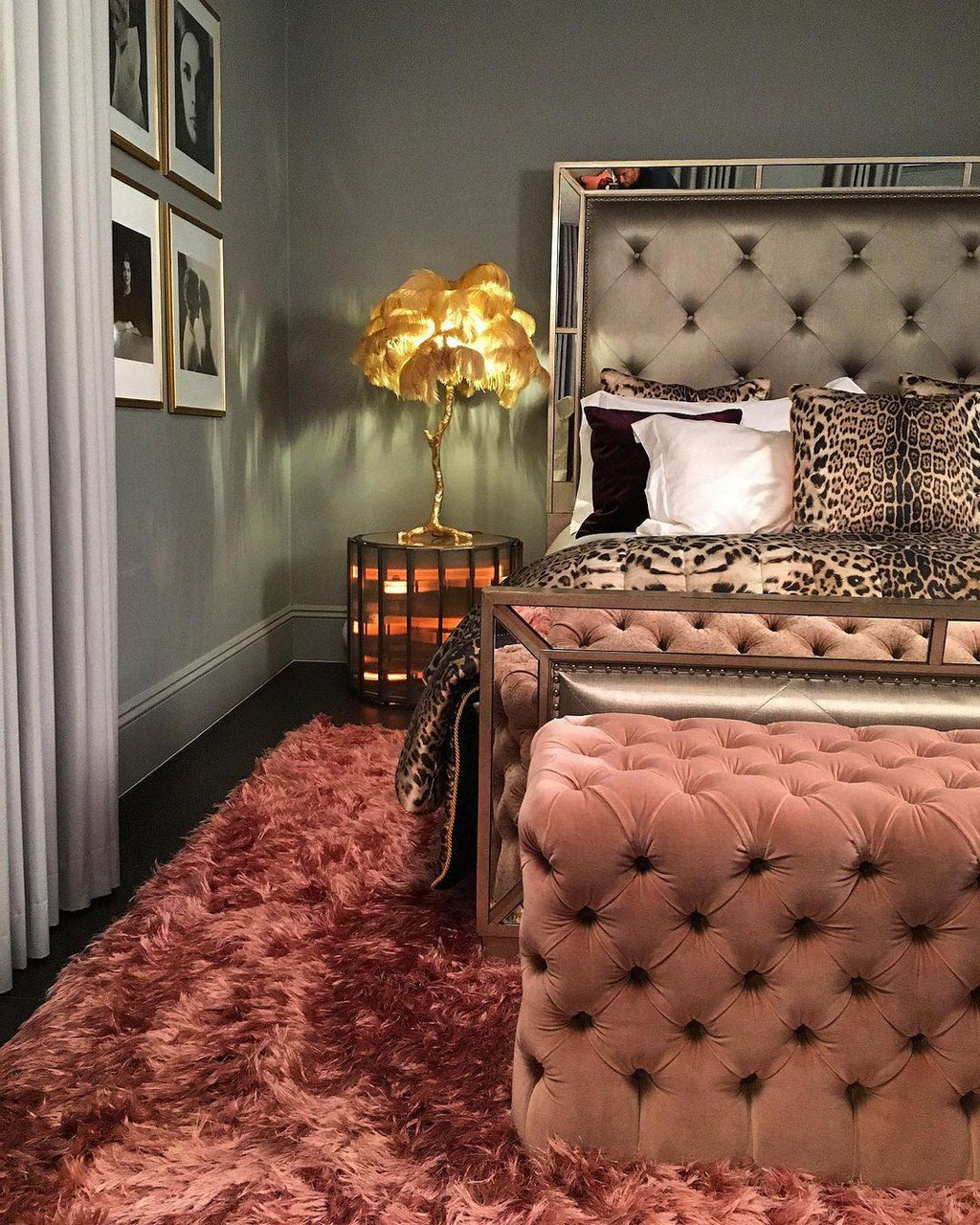 Closer view of a gold-feathered Clérachic table lamp beside a tufted bed with a leopard-print throw and a pink velvet ottoman.