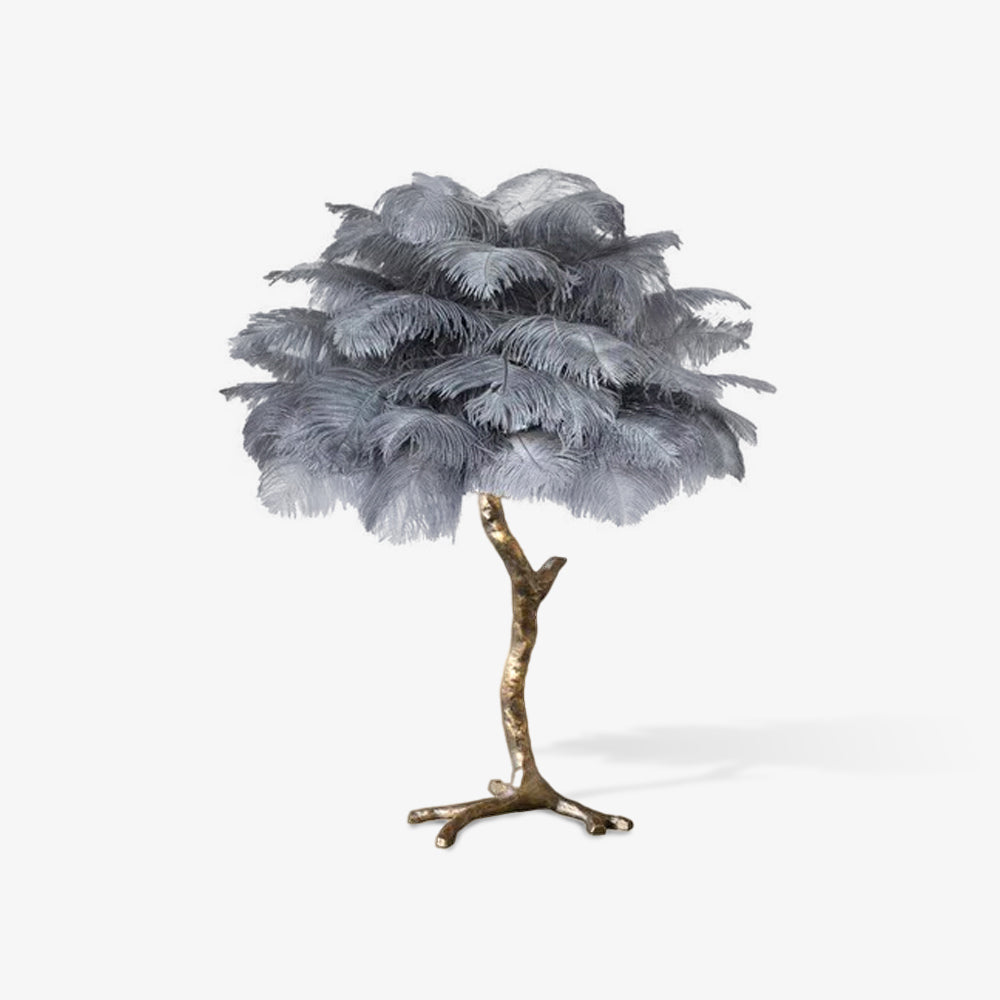 Clérachic table lamp with grey layered ostrich feathers on a gold branch stem, seen on a plain light backdrop with a soft shadow.