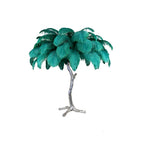 Clérachic table lamp with bright teal-green feathers on a silver branch stem with splayed feet, on a white background.