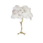 Clérachic table lamp with fluffy white ostrich feathers on a gold branch stem, shown on a white background.
