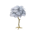 Clérachic table lamp with pale blue-grey feathers on a gold branch stem, shown on a white background.